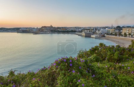 Photo for Beautiful orange sunset or sunrise over the harbor of Otranto, Italy. Soft clouds, calm ocean and backlit skyline and marina with yachts and fishermen. Touristic scenery in a horizontal frame - Royalty Free Image