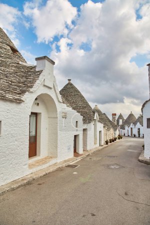 Photo for Alberobello, Puglia, Italy: Typical houses built with dry stone walls and conical roofs of the Trulli, in a beautiful day, Apulia - Royalty Free Image