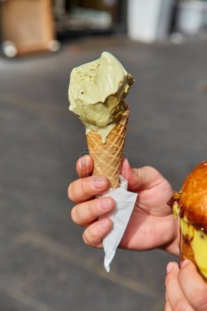 Foto de Cono de helado con helado de menta color pistacho en la ciudad. Refresco frío de verano. Deliciosa comida. - Imagen libre de derechos