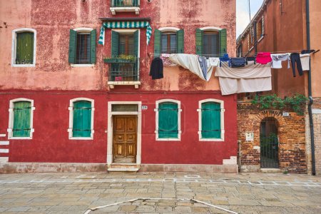 Photo for Typical city corner with ancient colorful building drying clothes on a clothes-line in outdoor at sunny summer day. Venice, Italy - Royalty Free Image