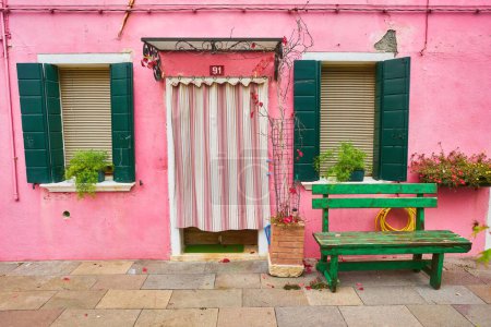 Foto de Una encantadora casa europea con dos ventanas, flores y persianas verdes - Imagen libre de derechos