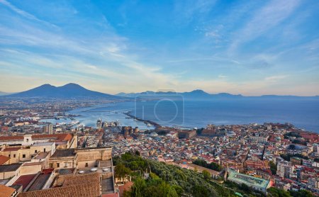 Photo for Naples, Italy: Panoramic view of the city and port with Mount Vesuvius on the horizon as seen from the hills of Posilipo. Seaside landscape of the city harbor and gulf on the Tyrrhenian Sea. - Royalty Free Image