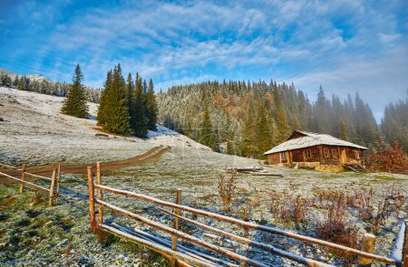 Photo for Autumn landscape with the first unexpected snow and fall foliage. Old wooden huts on a mountain hill - Royalty Free Image
