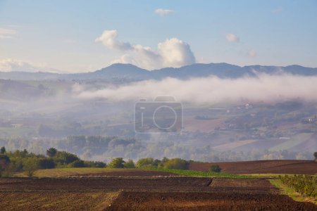 Photo for Ploughed field and rural hut against cloudy sky - Royalty Free Image