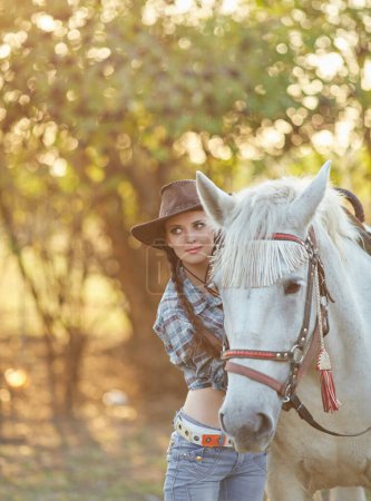 Téléchargez les photos : Joyeux cow-girl en chapeau étreignant son cheval - en image libre de droit