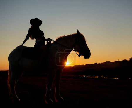 Photo for Horseback woman riding on galloping horse with red rising sun on horizon. Beautiful colorful sunset header background with equine and girls silhouette. - Royalty Free Image