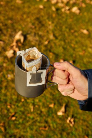 Photo for A cup of portable drip coffee is being prepared in the autumn mountains. Against the backdrop of wild nature - Royalty Free Image