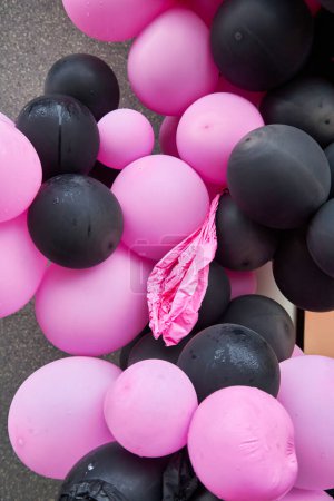Foto de Muchos globos inflables rosados y negros, con un globo rosado desinflado entre ellos. Foto conceptual, muestra el desvanecimiento de la individualidad entre los muchos. - Imagen libre de derechos