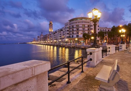 Téléchargez les photos : Bancs vides et lampadaires en bord de mer et promenade à Bari, Italie. Soirée romantique, calme et relaxante en ville. Le soleil se couche - en image libre de droit
