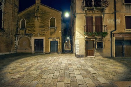 Photo for The beautiful architecture of Venice, Italy, by night with a little bridge over a canal lit up by streetlight - Royalty Free Image