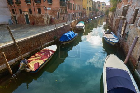 Foto de Barcos cubiertos de lluvia estacionados en el agua junto a la casa en el canal de Venecia. Transporte acuático y tema de transporte. Mañana en Venecia. - Imagen libre de derechos