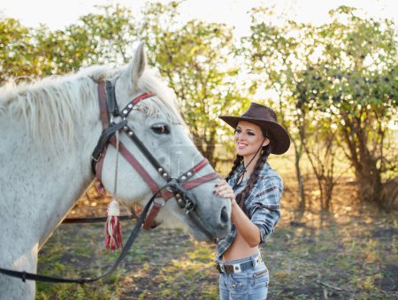 Foto de Feliz vaquera con sombrero abrazando a su caballo - Imagen libre de derechos