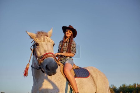 Foto de Hermosa chica montando un caballo contra el cielo azul - Imagen libre de derechos