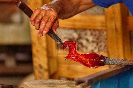 Photo for A Murano glass blower holds a red hot glass horse sculpture - Royalty Free Image
