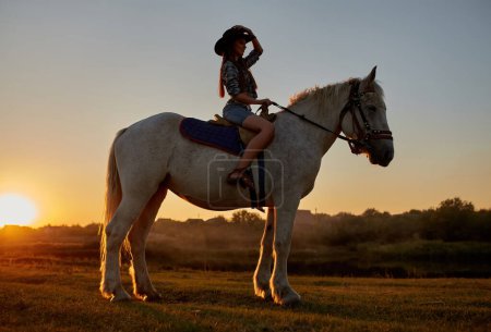 Foto de Silueta de vaquero, montar en caballo árabe semental en colorido atardecer. Concepto romántico para fondo safari - Imagen libre de derechos