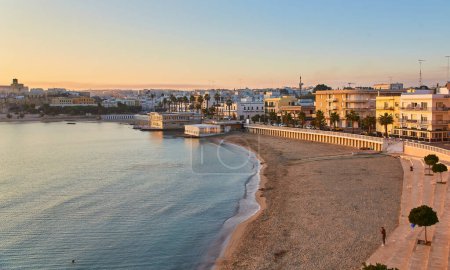 Téléchargez les photos : Magnifique coucher de soleil orange ou lever de soleil sur le port d'Otranto, Italie. Nuages doux, océan calme et horizon rétroéclairé et marina avec des yachts et des pêcheurs. Paysages touristiques dans un cadre horizontal - en image libre de droit
