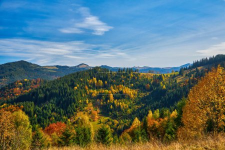 Foto de Mañana de otoño en las montañas: un pueblo sereno en el valle rodeado de majestuosos picos y colorido follaje - Imagen libre de derechos