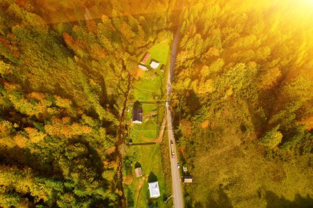 Téléchargez les photos : Vue aérienne des montagnes au lever du soleil en automne en Ukraine. Paysage coloré avec route de montagne, forêt, maisons sur les collines, lumière du soleil, ciel en automne. - en image libre de droit