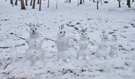 Téléchargez les photos : Une scène hivernale mettant en vedette cinq petits bonhommes de neige debout dans un parc. - en image libre de droit