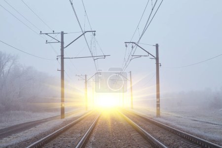 Foto de Una cautivadora escena donde las vías ferroviarias se desvanecen en la niebla invernal, creando una atmósfera etérea y enigmática. - Imagen libre de derechos