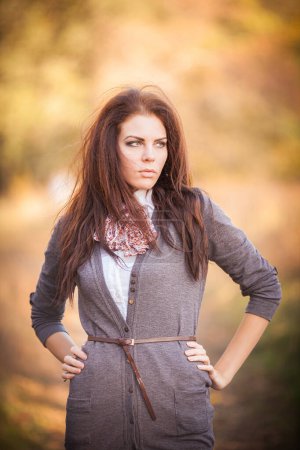 Photo for A captivating portrait of a brunette woman amidst the enchanting beauty of the autumn landscape. Her presence exudes grace and serenity as she embraces the colors of the season. Nature becomes the perfect backdrop for her radiance. - Royalty Free Image