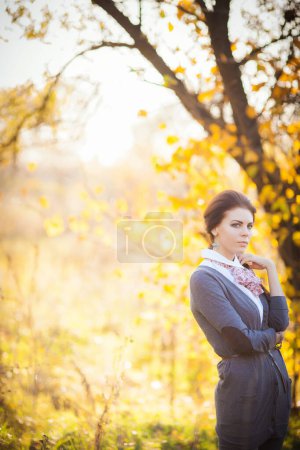 Téléchargez les photos : Capturée au milieu de la beauté fascinante de la forêt d'automne, une fille brune gracieuse rayonne d'élégance et de sérénité. Les couleurs vibrantes des feuilles tombantes et la lumière du soleil tamisée créent une toile de fond captivante pour sa présence. - en image libre de droit