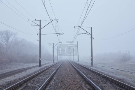 Photo for A glimpse into winter's onset - mist-shrouded dual railway tracks vanishing into the unknown, evoking an aura of mystery and transition - Royalty Free Image