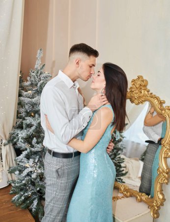 Foto de Joven pareja enamorada se para cerca del árbol de Navidad y abraza - Imagen libre de derechos