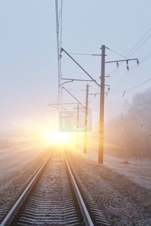 Foto de Una cautivadora escena donde las vías ferroviarias se desvanecen en la niebla invernal, creando una atmósfera etérea y enigmática. - Imagen libre de derechos