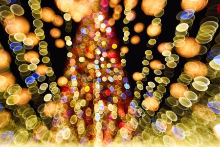 Foto de Árbol de Navidad borroso con decoraciones de luces al aire libre por la noche. Celebración de Año Nuevo. - Imagen libre de derechos