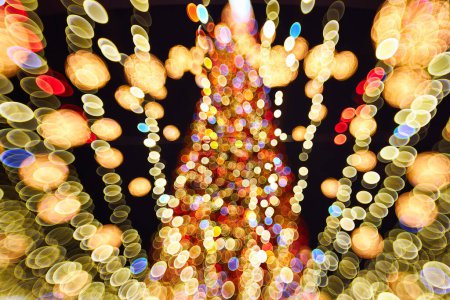 Téléchargez les photos : Arbre de Noël flou avec des décorations lumineuses à l'extérieur la nuit. Célébration du Nouvel An. - en image libre de droit