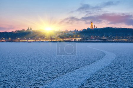 Téléchargez les photos : Embrassant l'enchantement de l'hiver, cette photo capture la beauté sereine de la rivière gelée Dnipro à Kiev, avec l'emblématique lavra de Kiev Pechersk à l'horizon. - en image libre de droit
