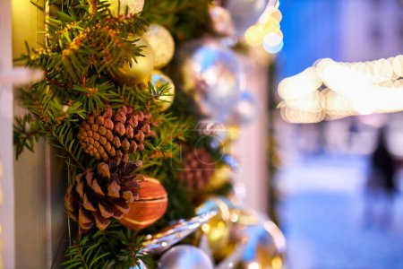 Téléchargez les photos : Les lumières de la guirlande décorent la maison et le sapin de Noël, sur la branche, il y a une boule rouge étincelante. Arbre de Noël dans la ville du soir la veille du Nouvel An. humeur de Noël. - en image libre de droit