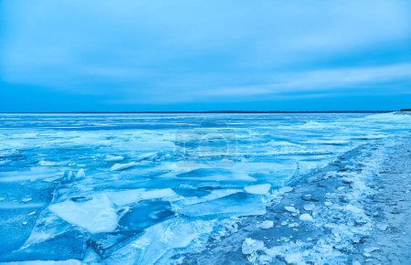 Photo for A captivating winter scene where pristine blue ice hugs the water's edge, delicately layering the shoreline in its crystal embrace - Royalty Free Image