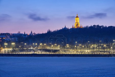 Téléchargez les photos : Alors que le soleil se couche lors d'une soirée d'hiver, la rivière Dnipro à Kiev se transforme en un chef-d'œuvre glacé et scintillant, offrant une vue imprenable sur l'emblématique lave de Kiev Pechersk - en image libre de droit