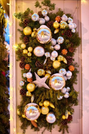 Foto de Las luces de la guirnalda decoran la casa y el árbol de Navidad, en la rama hay una bola brillante roja. Árbol de Navidad en la ciudad de la noche en la víspera de Año Nuevo. Humor de Navidad. - Imagen libre de derechos