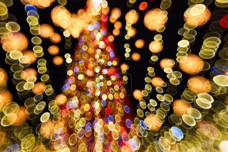 Téléchargez les photos : Noël et Bonne année brouillé bokeh. Photo authentique de lumière colorée sur l'arbre de Noël en plein air avec bokeh. Beau fond bokeh de Noël - en image libre de droit
