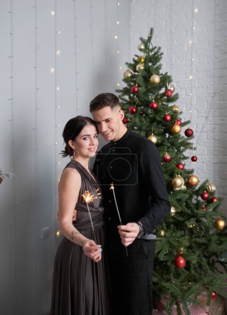 Photo for Beautiful couple in love. Cheerful young couple in elegant evening dresses. Fashion, glamour.hugging in christmas decorated interior - Royalty Free Image