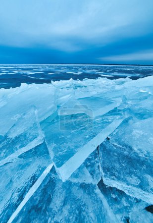 Foto de Una impresionante vista de invierno con una capa de hielo azul cristalino que cubre suavemente la orilla del lago en una impresionante exhibición de belleza natural congelada - Imagen libre de derechos