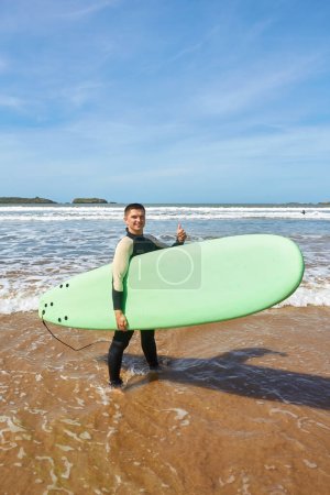 Photo for A young surfer strikes a pose with his board on the ocean's edge in Essaouira, capturing the essence of seaside adventure and surf culture. - Royalty Free Image