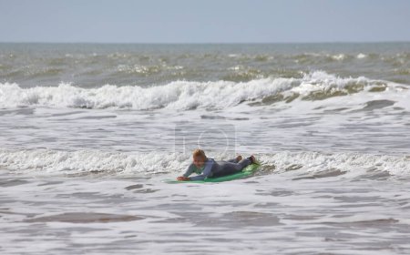 Téléchargez les photos : Une jeune surfeuse chevauche gracieusement les vagues sur sa planche le long des rives d'Essaouira, au Maroc, capturant le frisson et la beauté de la culture du surf contre le littoral pittoresque. - en image libre de droit