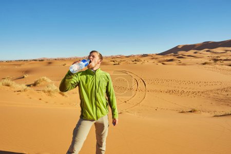 Foto de Un viajero solitario se encuentra entre las interminables dunas del Sahara, donde las arenas doradas se encuentran con el horizonte bajo el cálido sol. - Imagen libre de derechos