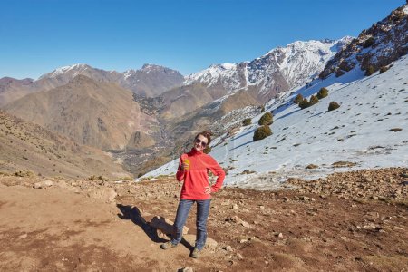 Téléchargez les photos : Un touriste sur le col de l'Atlas, avec des sommets enneigés derrière, capture la beauté sereine du paysage montagneux. - en image libre de droit