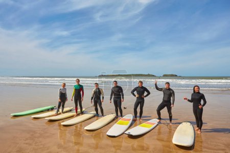 Photo for A group of young surfers captures a collective moment with their boards on the oceanfront in Essaouira, Morocco, showcasing the camaraderie and passion of coastal living. - Royalty Free Image