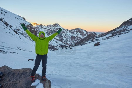Téléchargez les photos : Un touriste sur le col de l'Atlas, avec des sommets enneigés derrière, capture la beauté sereine du paysage montagneux. - en image libre de droit