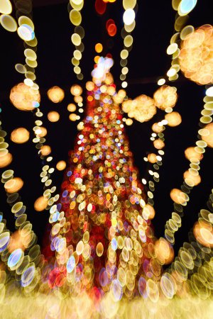 Téléchargez les photos : Arbre de Noël flou avec des décorations lumineuses à l'extérieur la nuit. Célébration du Nouvel An. - en image libre de droit