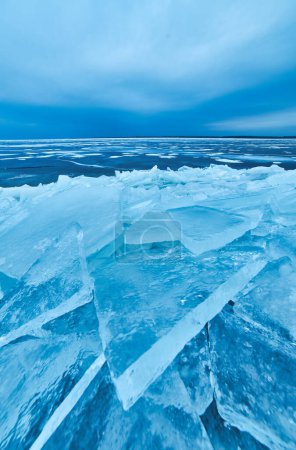 Photo for A striking winter view with a crystal-clear blue ice sheet gently encasing the lakeshore in a stunning display of frozen natural beauty - Royalty Free Image