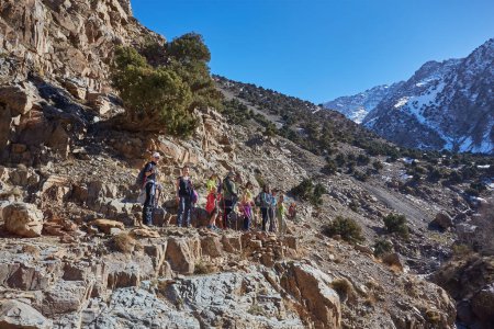 Téléchargez les photos : Un groupe de touristes trekking à travers les superbes montagnes de l'Atlas au Maroc, embrassant la beauté du terrain accidenté et se connectant avec la nature - en image libre de droit