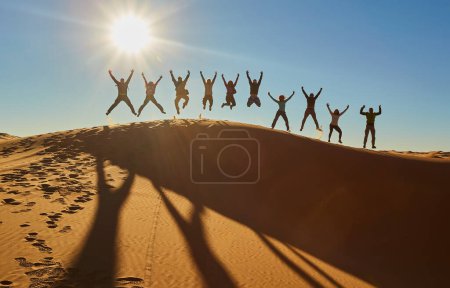 Téléchargez les photos : Un groupe de touristes capture des moments joyeux, pose ludique frappante, silhouette dans le contexte fascinant du désert du Sahara. Maroc. - en image libre de droit
