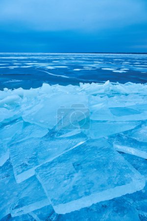 Téléchargez les photos : Une vue saisissante sur l'hiver avec une calotte glaciaire bleue cristalline enveloppant doucement le bord du lac dans un magnifique affichage de beauté naturelle gelée - en image libre de droit